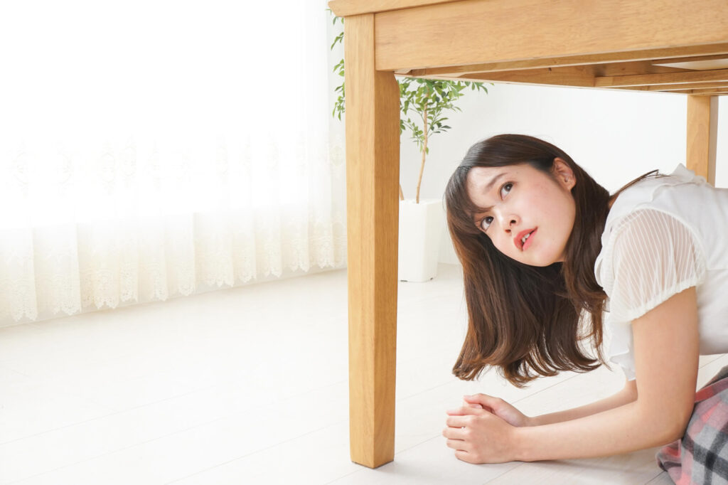 机の下に隠れる