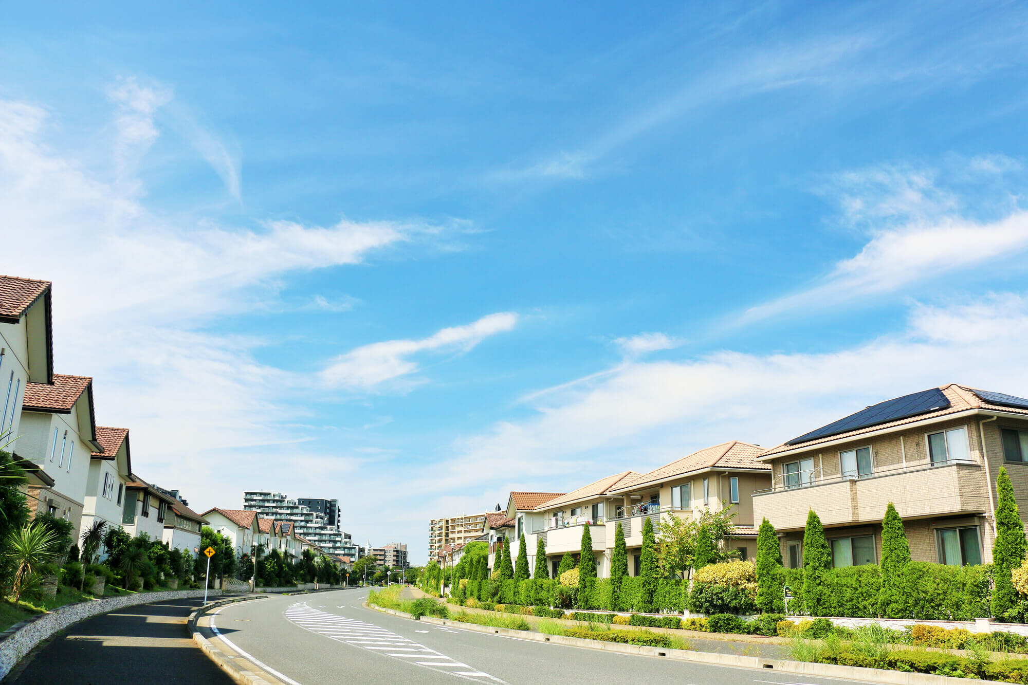 青空が広がる住宅街の道路と並ぶ住宅